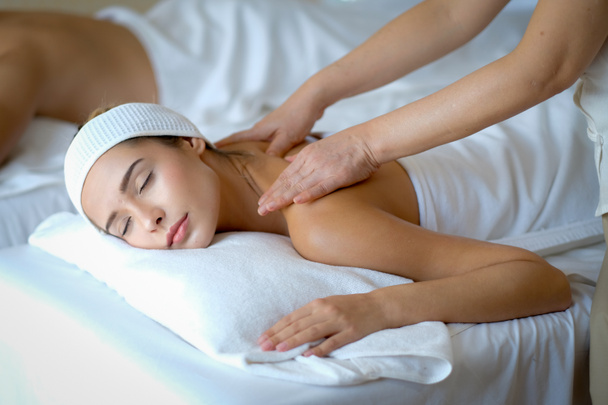 Jeune belle femme profiter avec massage dans la salle de spa avec la lumière du jour et l'autre homme se trouvent sur le lit à côté d'elle
. - Photo, image