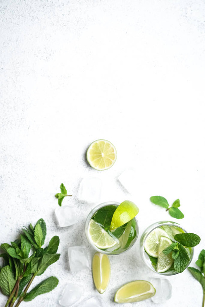 Refreshing mojito cocktail  with mint, rum and lime, cold drink or beverage with ice on white background, top view - Photo, Image