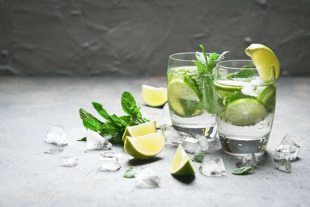 Refreshing mojito cocktail  with mint, rum and lime, cold drink or beverage with ice on dark stone table. - Zdjęcie, obraz