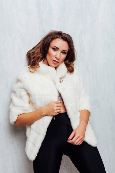 portrait of a beautiful fashionable woman with hair curls in a white fur coat in winter - Photo, Image