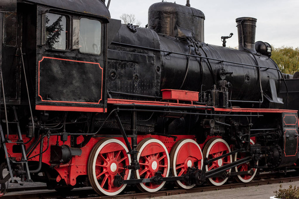 Old black and red retro steam locomotive at the railway station. Vintage train staying on the railroad. - Photo, Image