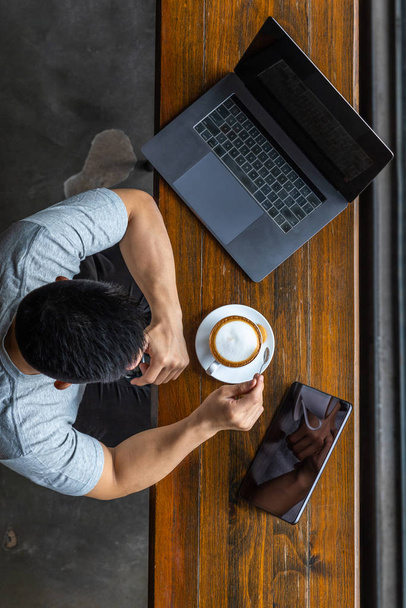 Κάθετη άποψη του Ασιάτη freelancer χρησιμοποιώντας laptop στην καφετέρια - Φωτογραφία, εικόνα