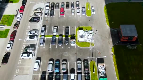 Luchtfoto van parkeren met veel auto 's in de buurt van groen gazon. Beweging. Bovenaanzicht van parkeerplaats met betonnen bestrating op een zomerse zonnige dag. - Video