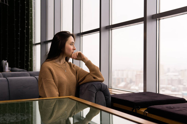 fiatal nő néz figyelmesen ki az ablakon egy téli napon - Fotó, kép
