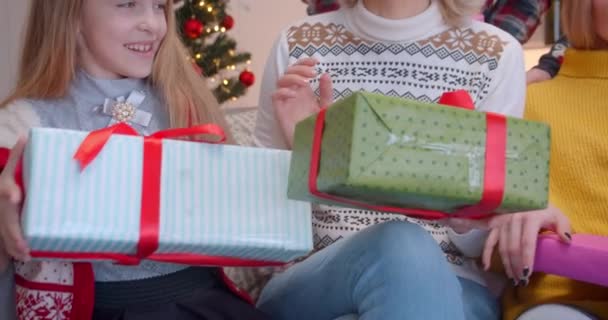 Κοντινό πλάνο Η μεγάλη οικογένεια που κάθεται στον καναπέ δίνει ο ένας στον άλλο Χριστουγεννιάτικα δώρα - Πλάνα, βίντεο