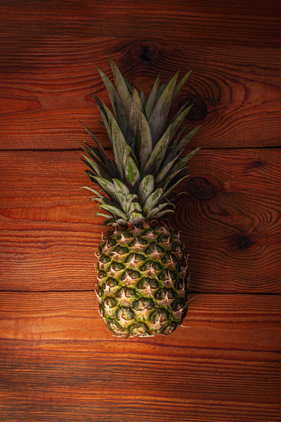 Ripe pineapple on wooden background. Healthy food ingredients, tropical fruits, diet, slimming vegan foods, weight loss. - Photo, image