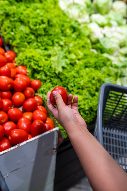 Mujer recogiendo tomate fresco a mano en el supermercado
 - Foto, imagen
