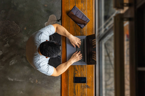 Asian freelancer typing laptop next to tablet and smart phone - Fotó, kép