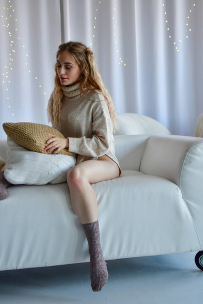  сексуальная девушка лежит на диване и играет с подушкой в свитере
 - Фото, изображение
