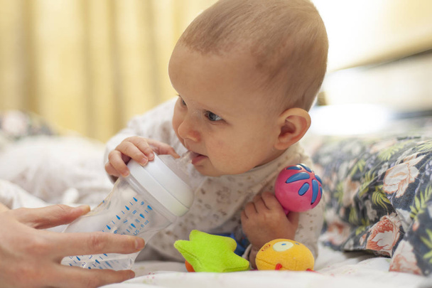 Baby drinks from a baby bottle. - Foto, Bild