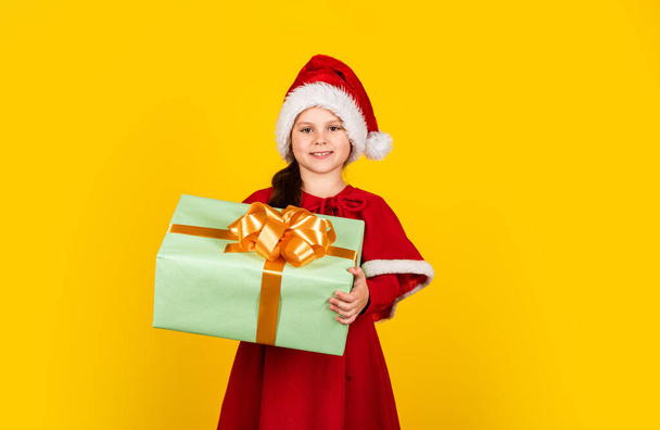 Time to celebrate. smiling child in santa hat. let your xmas be bright. childhood happiness. little elf hold gift box. new year preparation. christmas shopping time. toy shop and gifts for children - Foto, Imagen