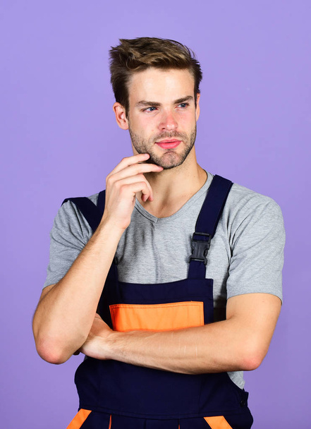 Assemble and set up machinery or equipment. Thoughtful repairman. Handsome repairman. Worker violet background. Man repairman builder in work clothes. Troubleshoot and fix faulty electrical switches - Fotoğraf, Görsel
