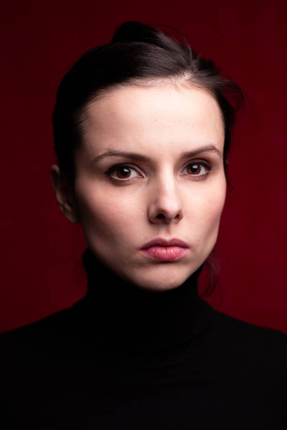 emotional girl in a black turtleneck on a red background - Foto, imagen
