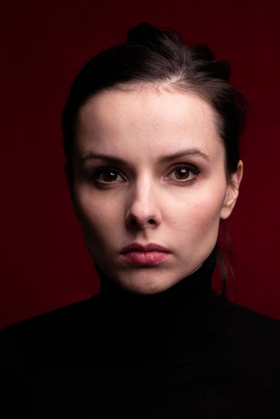 emotional girl in a black turtleneck on a red background - Foto, afbeelding