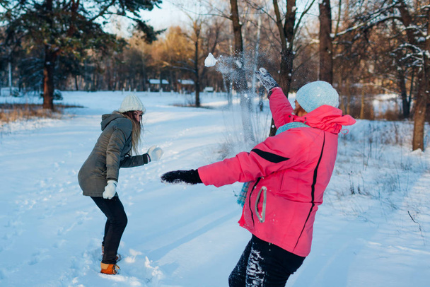 Lumipalloja leikkimässä talvimetsässä. Perhe äiti ja tytär hauskaa heittää lunta ulkona
 - Valokuva, kuva