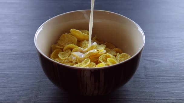 Milk is pouring in Corn Flakes on wooden background - Video