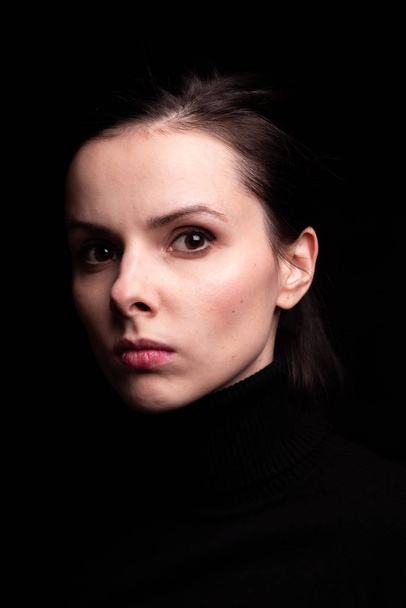 emotional girl in a black turtleneck on a black background - Fotografie, Obrázek