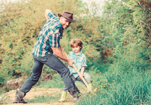Cute child in nature having fun with cowboy dad. Find treasures. Little boy and father with shovel looking for treasures. Happy childhood. Adventure hunting for treasures. Little helper in garden - Фото, изображение