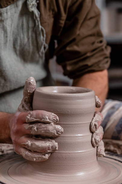 Potter making a jar pot of white clay on the potter's wheel circle in studio, concept of creativity and art, vertical photo - Foto, afbeelding