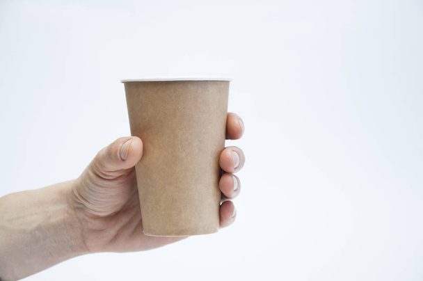Χάρτινο κύπελλο για καφέ και τσάι στο χέρι. Σε λευκό φόντο - Φωτογραφία, εικόνα
