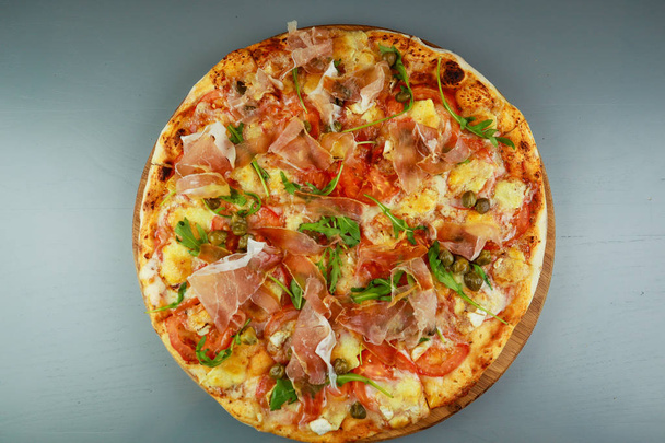 Die Pizza ist Schinken. Kapern, Tomaten, Rucola, Mozzarella,  - Foto, Bild