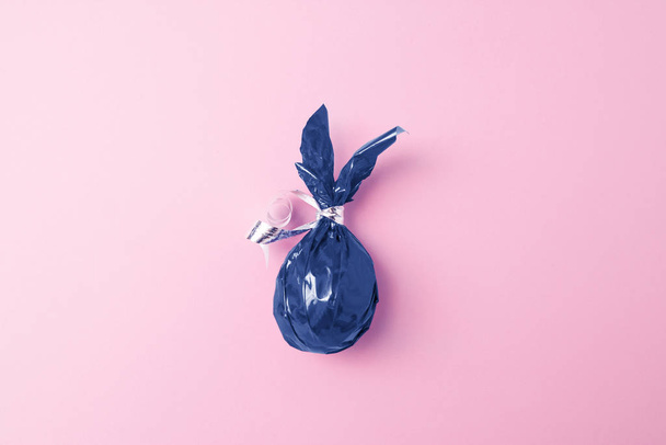 Creative easter greeting card with colored blue Egg bunny ears on pink background. Flat lay, minimal style, copyspase. Trendy classic blue color of the year 2020. - Foto, imagen