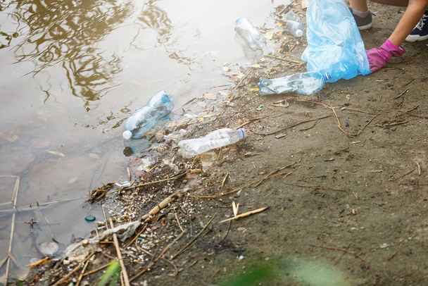 Un volontaire ramasse des bouteilles en plastique sales dans le parc. Les mains ramassent les ordures, ramassent les ordures dans le sac. Eco activiste nettoyer la nature du plastique. - Photo, image