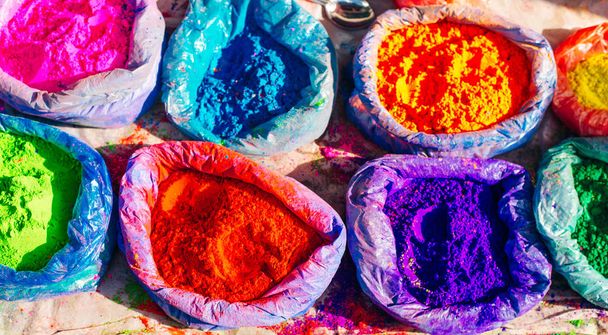 πολύ φωτεινή πολύχρωμη σκόνη χρώματος σε σακούλες και ένα μικρό κουτάλι. μπογιές για τις διακοπές του Holi - Φωτογραφία, εικόνα