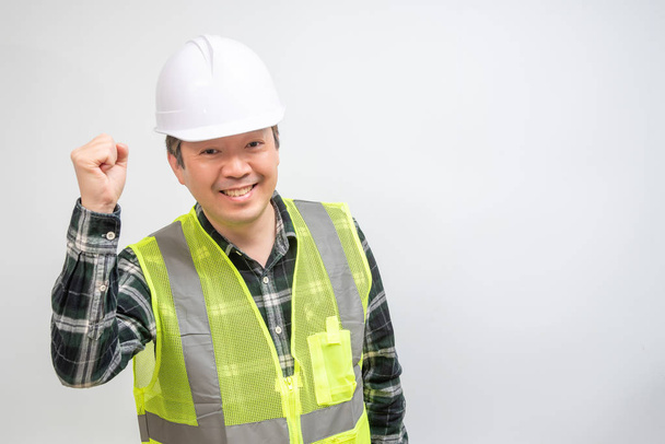 Asiático hombre de mediana edad en un chaleco de trabajo verde claro y sombrero de seguridad blanco
. - Foto, Imagen