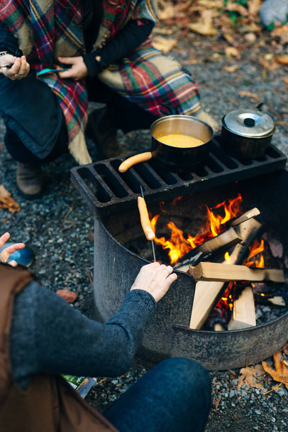 Bonfire worstjes op een kampvuur met een rooster op de achtergrond. - Foto, afbeelding
