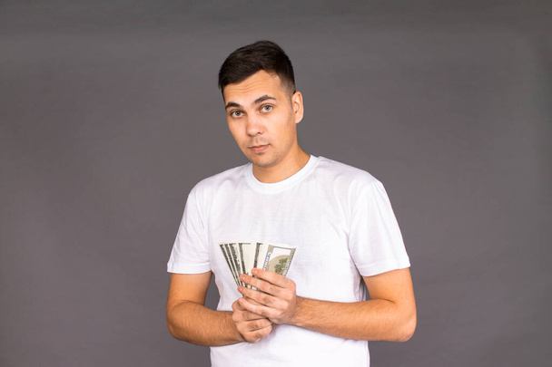 ein junger Mann hält ein großes Bündel Banknoten in der Hand - Foto, Bild