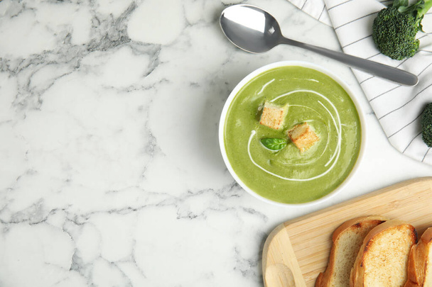 Delicious broccoli cream soup with croutons served on white marble table, flat lay. Space for text - Фото, изображение