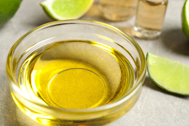 Lime essential oil in bowl on light table, closeup - Fotografie, Obrázek