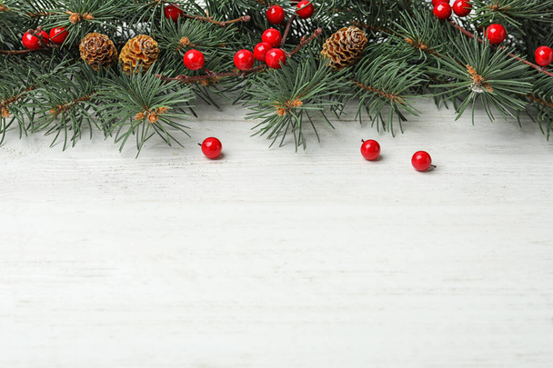 Composition with fir branches and berries on white wooden background, space for text. Winter holidays - Foto, afbeelding
