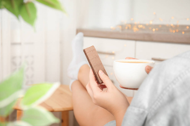 Woman having delicious wafer and coffee for breakfast indoors, closeup - Foto, Imagem