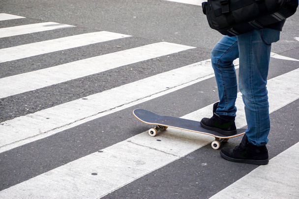 公園の道路でスケートボードをしているティーネージャーの足を閉じる. - 写真・画像