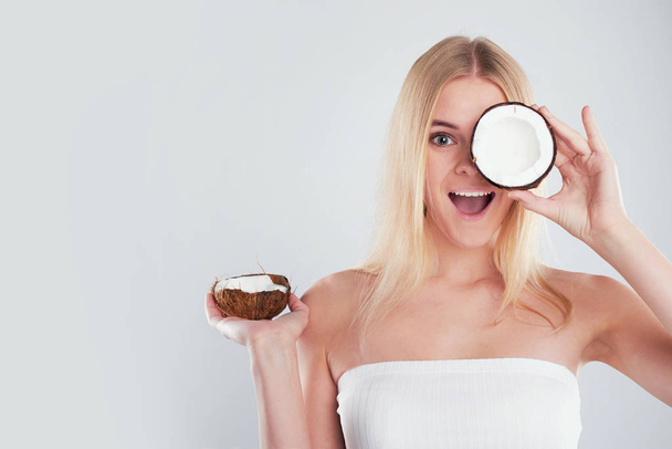 beautiful young girl with bare shoulders holds a coconut in her hands. skin care concept, spa salon - Photo, Image
