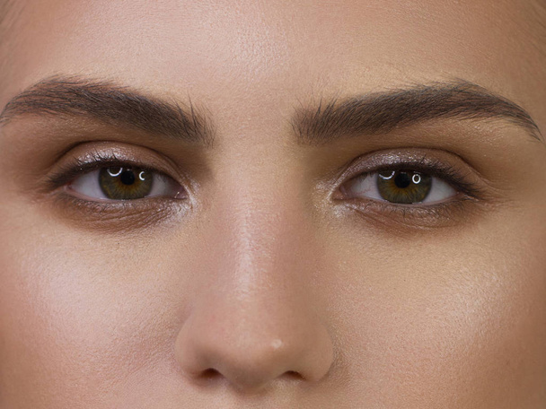 Close-up of woman's eyes with evening make-up. Fashionable shades of eye shadow, extremely long eyelashes and thick smooth eyebrows. Open beautiful look. Clean skin - Foto, Imagen