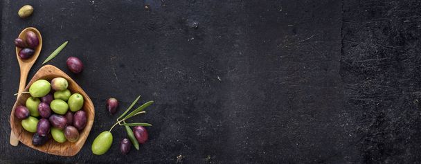 Ansicht von Bio-Olivenfrüchten auf rustikalem schwarzem Hintergrund.  - Foto, Bild