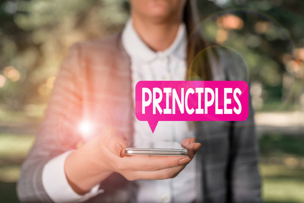 Writing note showing Principles. Business photo showcasing fundamental truth that serves as the base for a system of belief Woman in grey suites holds mobile phone. - Photo, Image