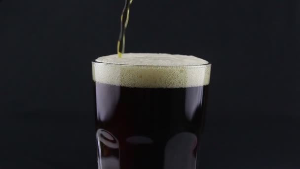 Barman giet donker bier uit een fles in een glas. Een man vult een glas met donker bier. - Video