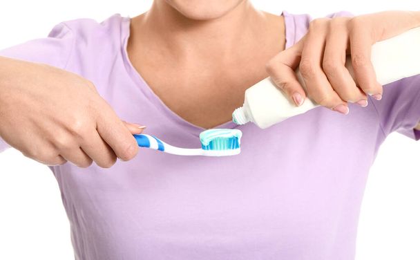 Jonge vrouw met tandenborstel en plak op witte achtergrond - Foto, afbeelding