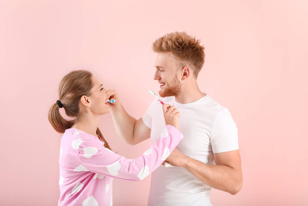 Young couple brushing teeth on color background - Foto, Bild