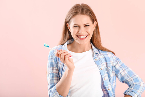 Young woman with toothbrush on color background - 写真・画像