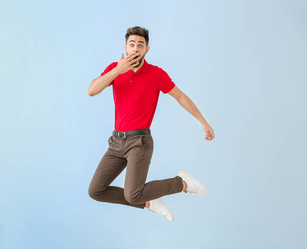 Σοκαρισμένος πηδώντας νεαρός άνδρας στο φόντο χρώμα - Φωτογραφία, εικόνα