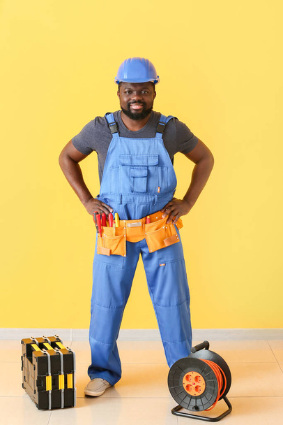 Electricista afroamericano cerca de la pared de color
 - Foto, imagen