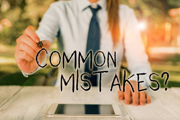 Text sign showing Common Mistakes Question. Conceptual photo repeat act or judgement misguided making something wrong Female business person sitting by table and holding mobile phone. - Photo, Image