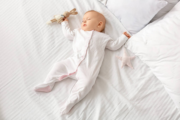 Oyuncak bebekli tatlı bebek yatakta uyuyor. - Fotoğraf, Görsel