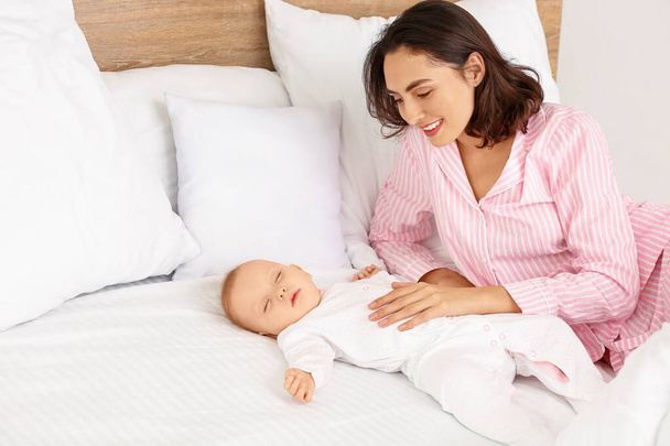 Mujer joven y su bebé durmiendo en la cama
 - Foto, Imagen