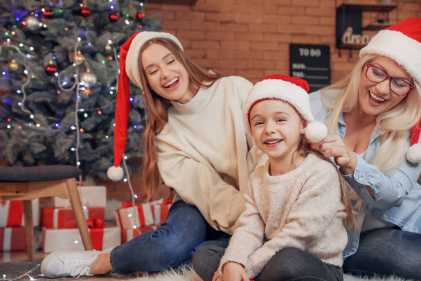 Noel arifesinde küçük kızı ve annesiyle birlikte evde genç bir kadın. - Fotoğraf, Görsel
